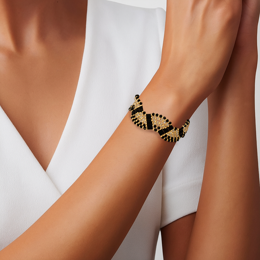 Bracelet handwoven with black and matte gold crystal beads in a geometric pattern, on a wrist