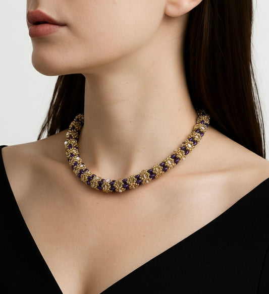 Handmade beaded necklace in gold and violet tones, floral pattern, shown worn around the neck.