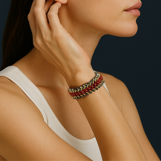 Close-up of a woman’s wrist wearing the Jardin ‘Nomade’ garnet-red beaded bracelet, shimmering against a deep teal backdrop