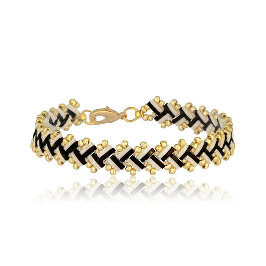 Bracelet with gold, black, and ivory T pattern on a white background