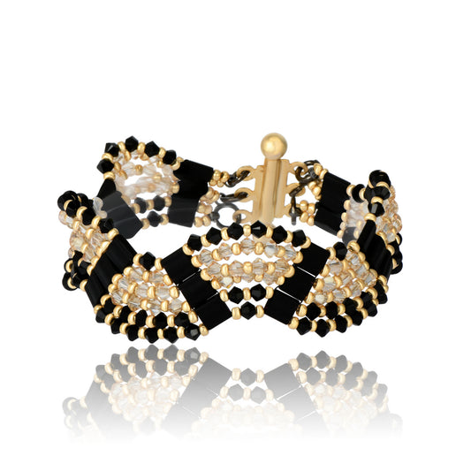 Bracelet handwoven with black and matte gold crystal beads in a geometric pattern, on white background