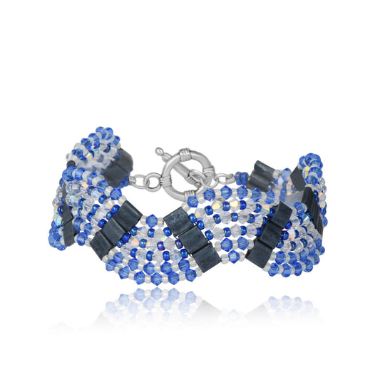 Bracelet handwoven with sapphire blue and silver crystal beads in a geometric pattern, on white 